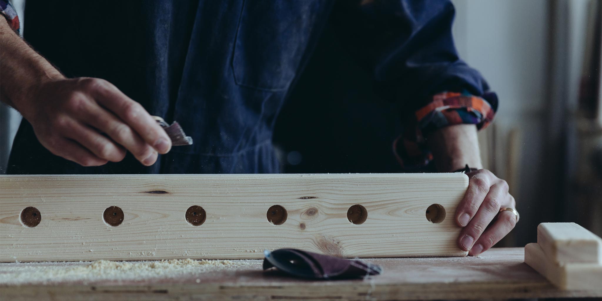 Close up image of Boot & Saw owner, Tristan Harris sanding part of a wellington rack