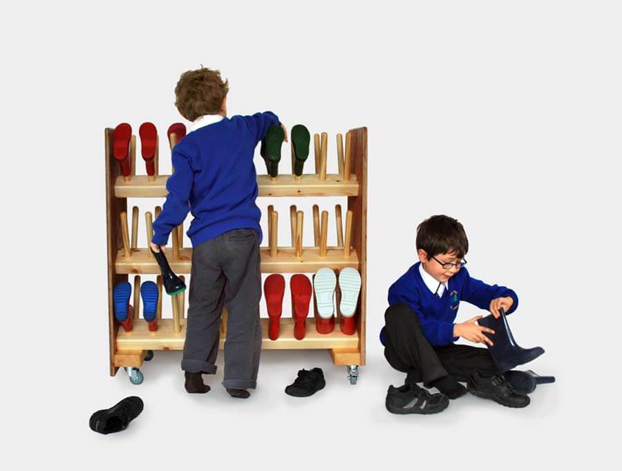 Two children putting welly boots on a school wellington rack supplied by Boot & Saw