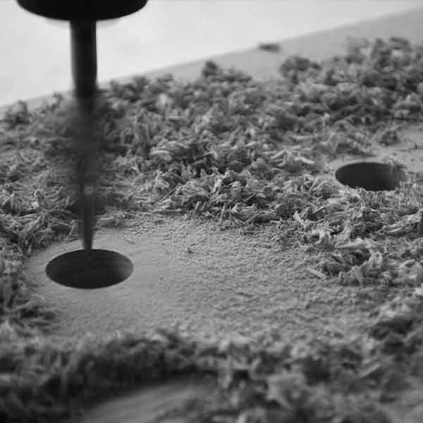 A drill making a hole and waste sawdust in a piece of European Oak