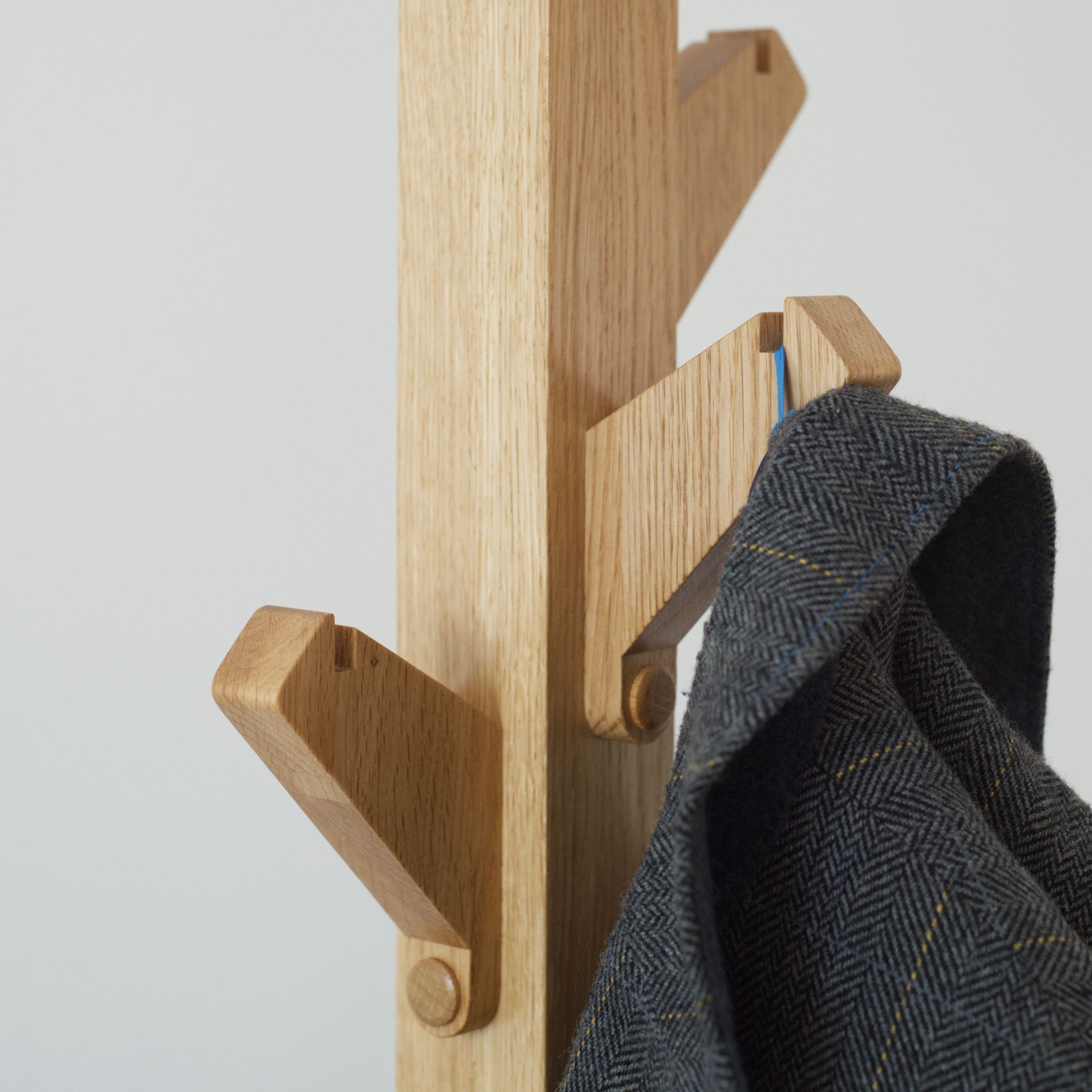 Wooden coat tree coat stand with hand made hooks in detail showing coat loop slot.