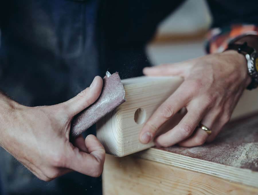 Close up of hands sanding a wooden boot rack