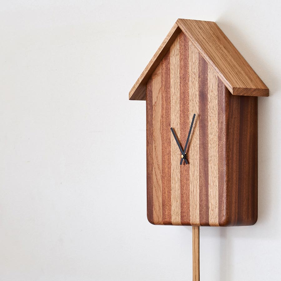 Oak and Mahogany 'Cuckoo-less' Clock hanging on a white wall, part of our accessories range